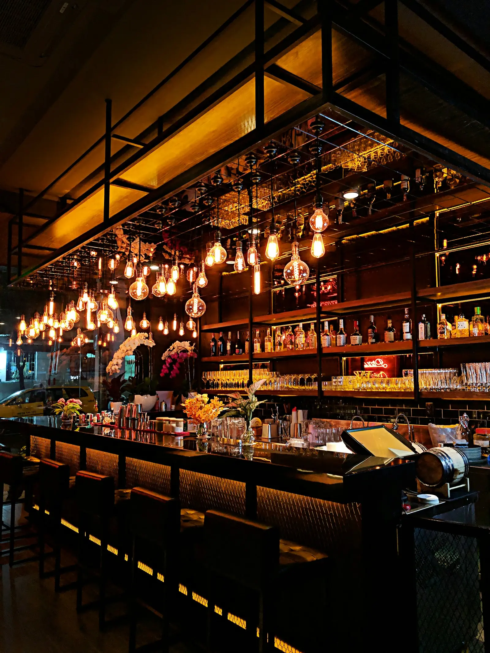 A warmly lit restaurant bar with glowing pendant bulbs