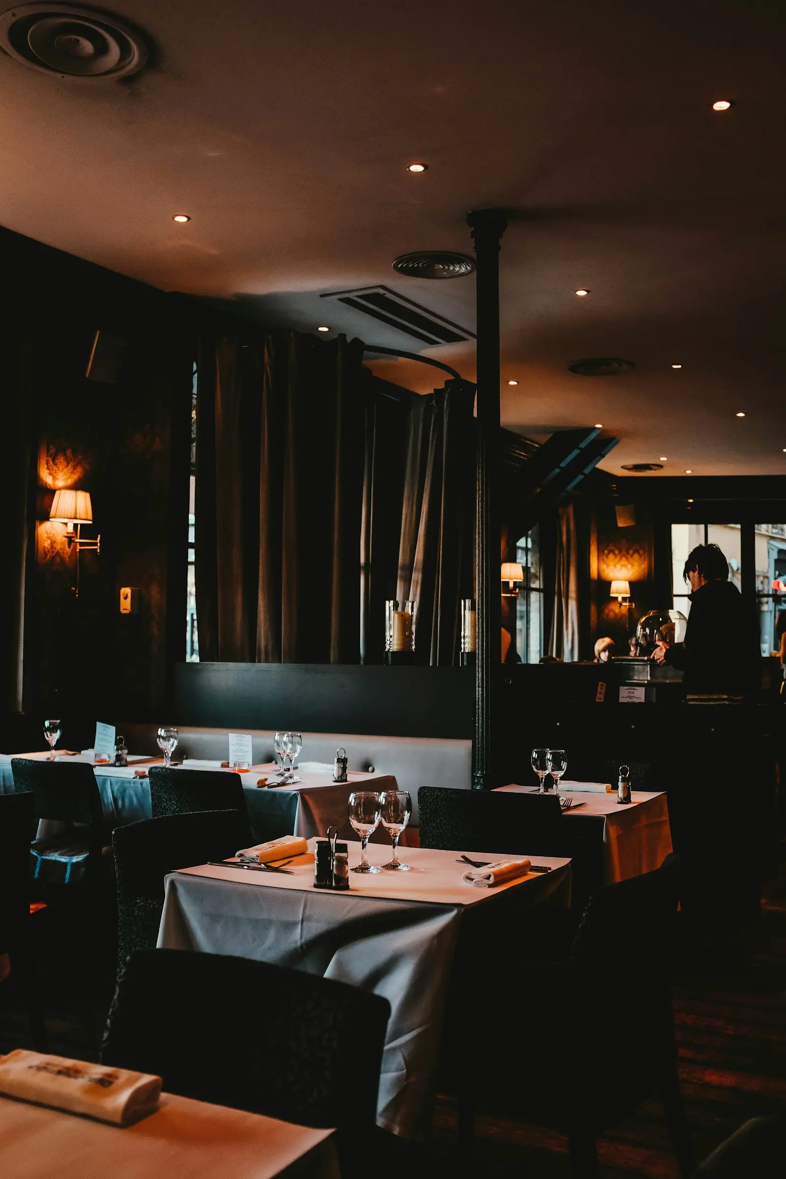 An intimate, softly lit dining room with tables set for the evening